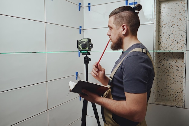 Tiler checks tile laying with building measuring laser level