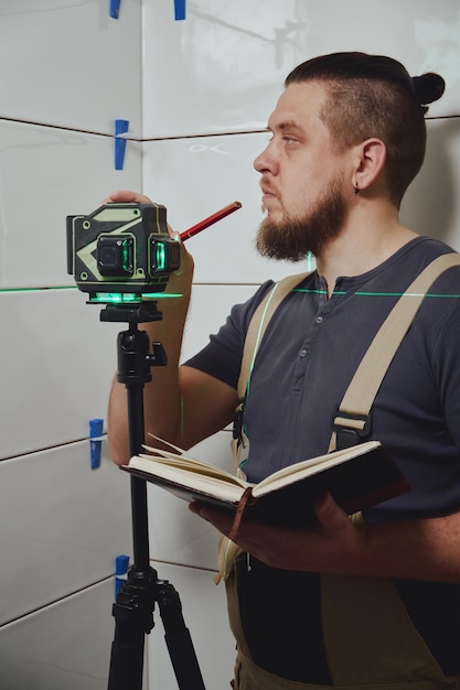 Tiler checks tile laying with building measuring laser level