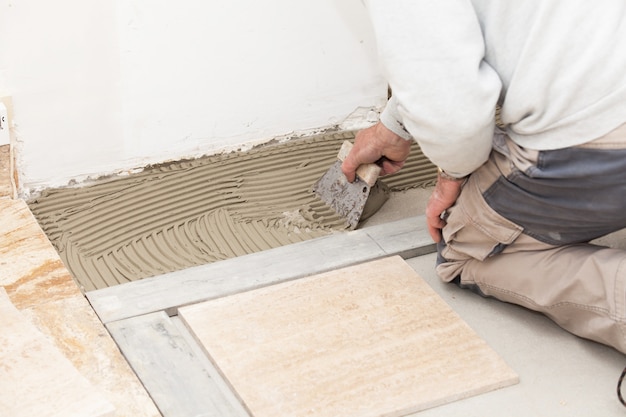 Photo a tiler laying a tiled marble