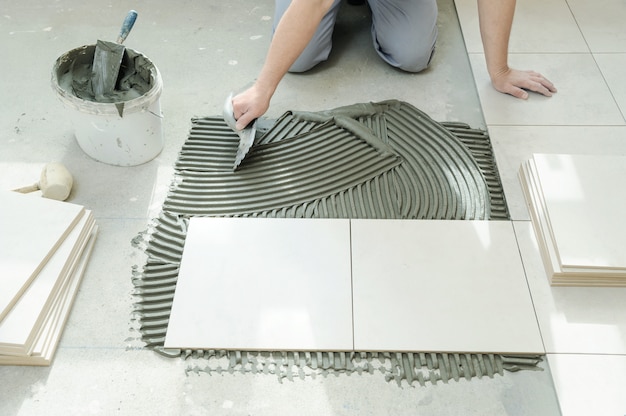 Tiler putting tiles adhesive to the wall with the notched trowel