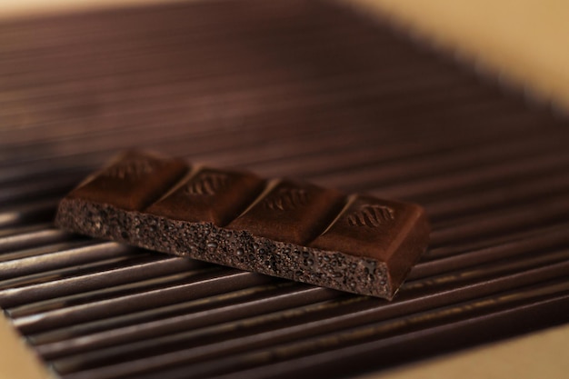 Tiles of dark chocolate on a cardboard box packed with chocolate. Close up