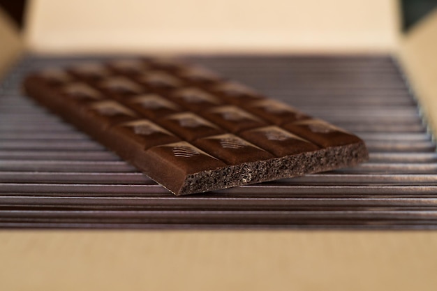 Tiles of dark chocolate on a cardboard box packed with chocolate. Close up