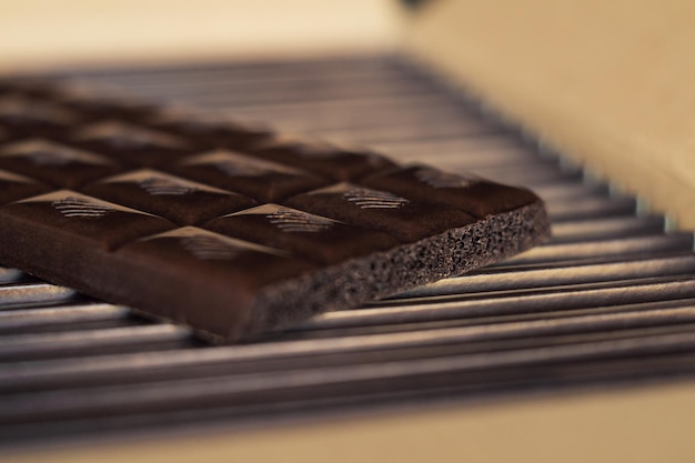 Tiles of dark chocolate on a cardboard box packed with chocolate. Close up