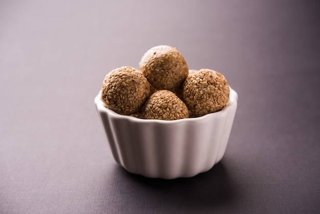 Tilgul Laddu or Til Gul balls for makar sankranti, it's a healthy food made using sesame, crushed peanuts and jaggery. served in a bowl. selective focus showing details.