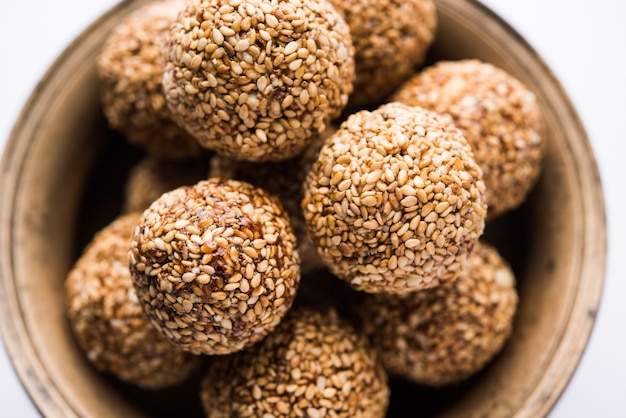 Tilgul Laddu or Til Gul balls for makar sankranti, it's a healthy food made using sesame, crushed peanuts and jaggery. served in a bowl. selective focus showing details.