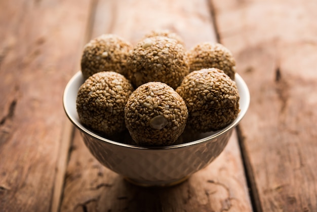 Tilgul Laddu or Til Gul balls for makar sankranti, it's a healthy food made using sesame, crushed peanuts and jaggery. served in a bowl. selective focus showing details.