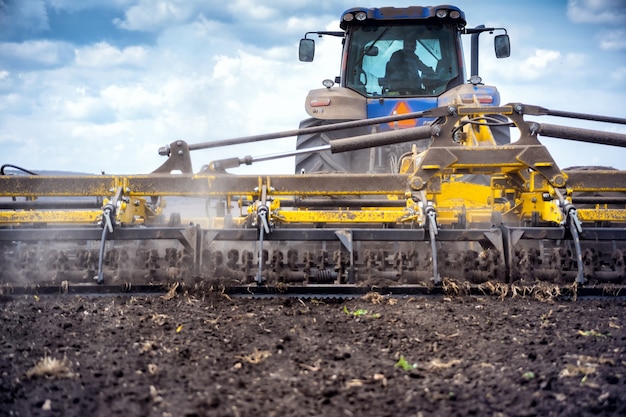 Tillage in the field with a tractor with a trailed machine.