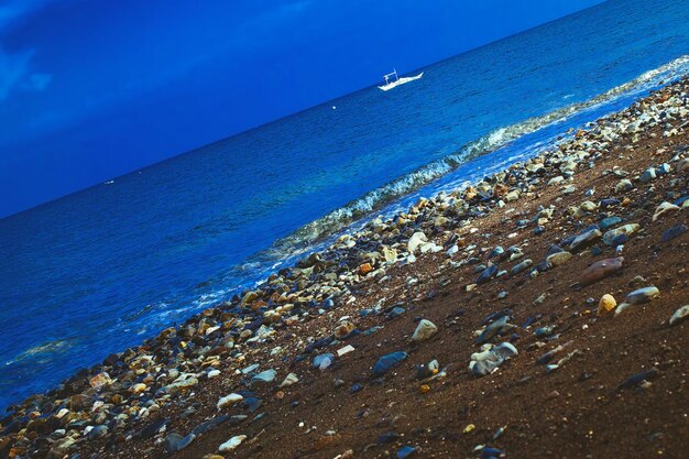 Tilt image of stones on beach against blue sky