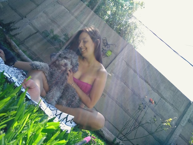 Photo tilt image of young woman sitting with dog in yard