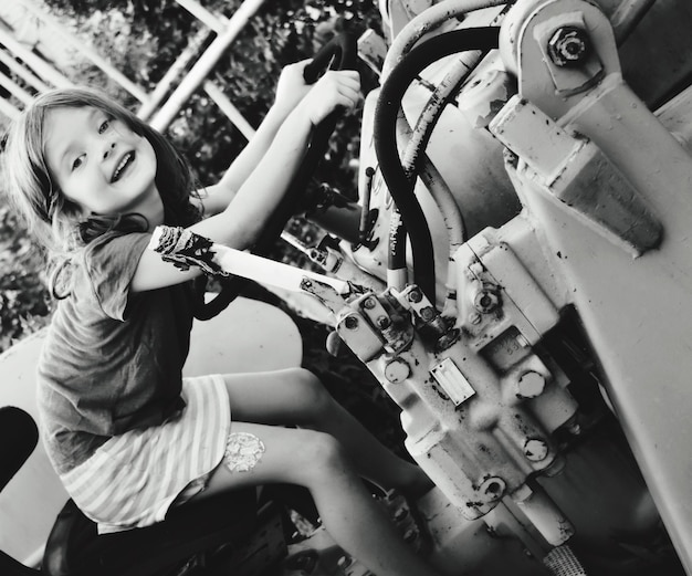 Foto tilt portret van een meisje dat op een tractor zit