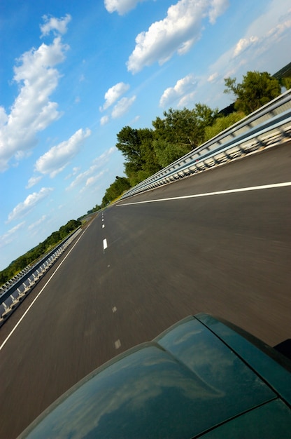 L'angolo inclinato ha sparato un'autostrada liscia circondata da una splendida natura estiva con erba verde e cielo blu con nuvole in una calda giornata estiva di sole