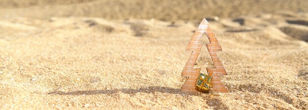 Timber wooden Christmas tree on a sand on the tropical beach near ocean, summer Christmas