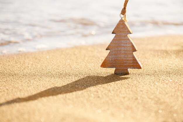 写真 海の近くの熱帯のビーチの砂の上のクリスマスツリーの木の木製の装飾