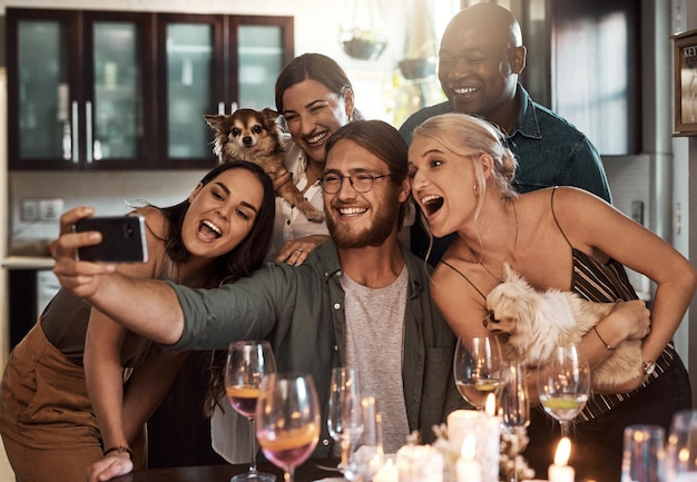 Time to celebrate Cropped shot of a group of cheerful young friends taking a self portrait together with a cellphone during christmas time