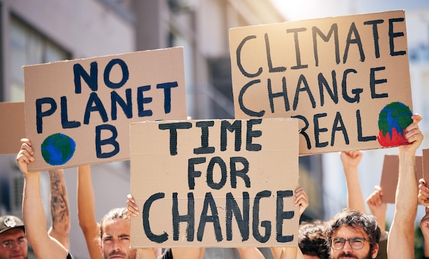 the time for change is now shot of a group of people holding up signs at a protest rally