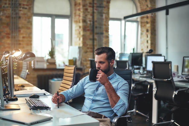 Photo time for coffee side view of young bearded businessman in formal wear working on computer