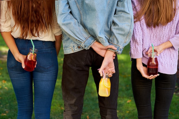 Time to detox. Youth with fruit juice cocktails on green summer nature background.