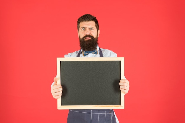 Time for dinner brutal waiter in kitchen mature man red backdrop scared hipster bartender What to cook Restaurant menu cafe shop advertisement bearded man chalkboard copy space Dont like it