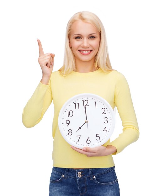 time, education and people concept - smiling young woman with wall clock showing 8 and finger up