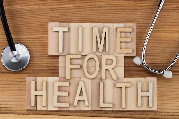 健康のための時間-聴診器を備えた木製のブロック上のヴィンテージ文字のテキスト。医学の概念。