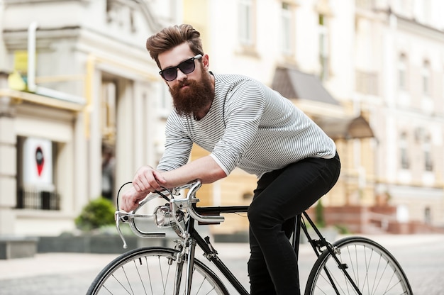 道に出る時間です。屋外で自転車に座ってカメラを見ているハンサムな若いひげを生やした男