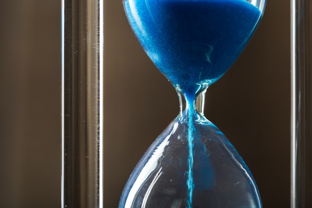 Time is passing. Blue hourglass close up