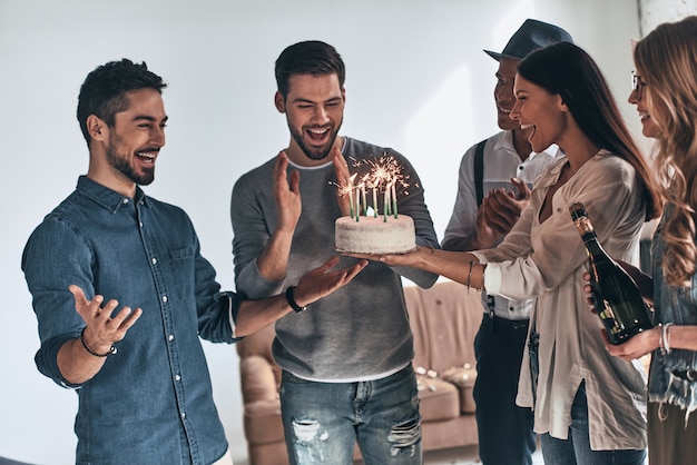 願い事をする時間。友人の間で誕生日を祝いながら身振りで示すと笑顔の幸せな若い男