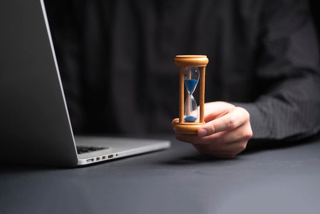 A time management concept businessman holding hourglass