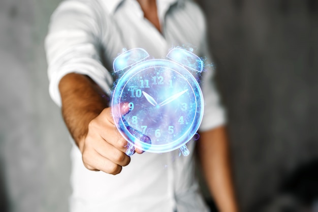 Foto concetto di gestione del tempo, un uomo mostra un ologramma di un primo piano dell'orologio. copia spazio.