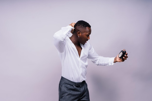 Time management concept shocked black man holding wall clock running out of time