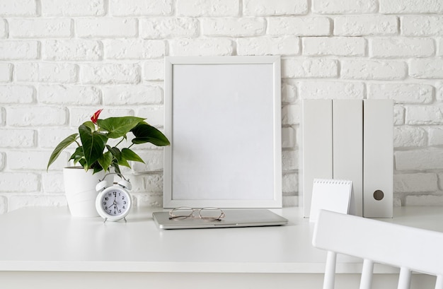 Time management, planning concept. front view of desk\
arrangement with blank calendar for mock up, paper folders and\
white frame in room interior. mock up design