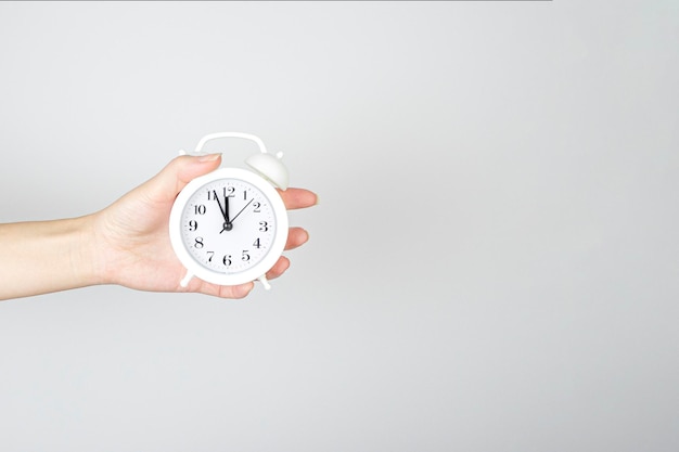 Time management punctuality awakening concept Hand holding alarm clock on light background