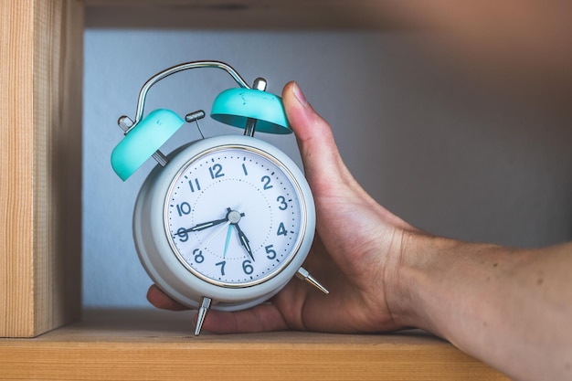 Time and morning concept Retro styled alarm clock in a wooden bookshelf