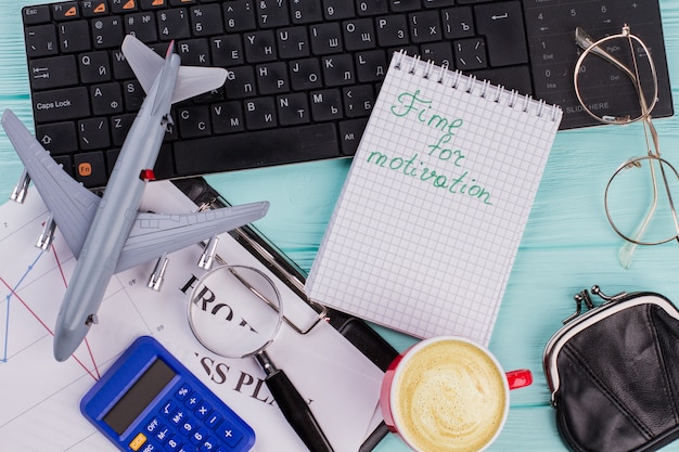 Photo time for motivation on notebook with office accessories and airplane on wooden table top background. flat lay compostion.