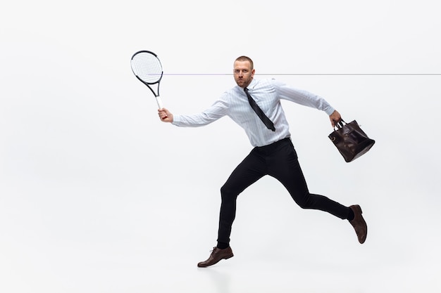 Time for movement. Man in office clothes plays tennis isolated on white studio background.