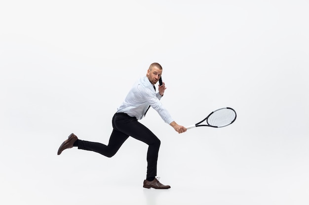 Time for movement. Man in office clothes plays tennis isolated on white