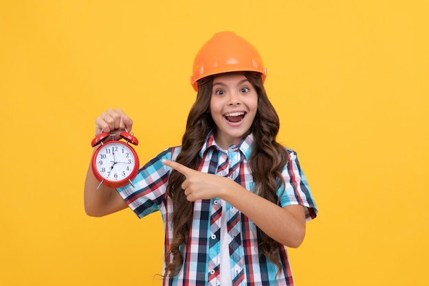 Time to renovate deadline extended early morning future career making repair amazed teen girl point finger on clock child in helmet time for decoration kid education renovation work