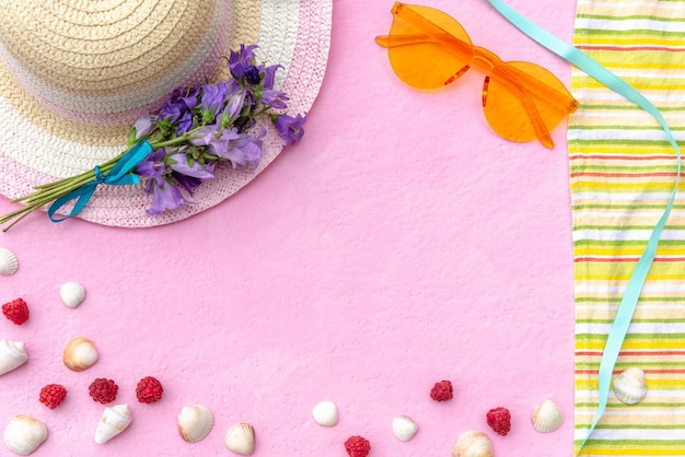 Foto tempo per riposare. cappello, occhiali da sole e copriletto su fondo rosa.