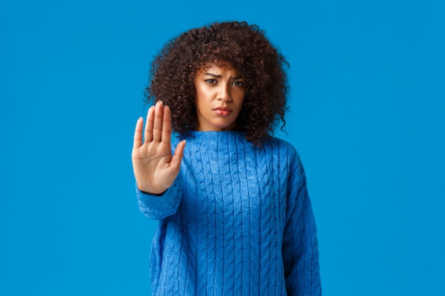 Time to stop. Sinecere and upset, gloomy young caring african american female friend trying prevent bad things, pulling hand in forbid, prohibition or disagree gesture, warning over blue background