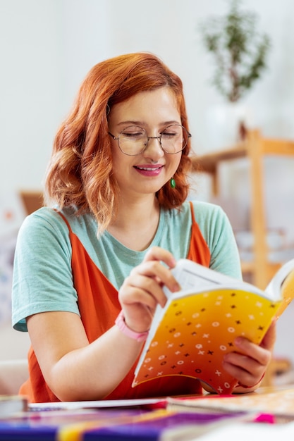 Tempo o studio. piacevole giovane donna che guarda nel suo quaderno mentre studia