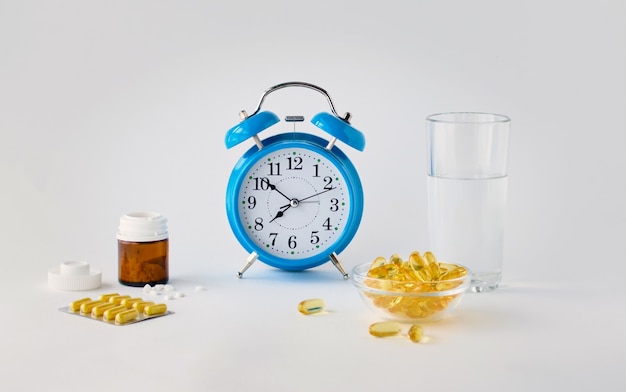 Photo time to take your pills an alarm clock on a white background shows the time of taking medication