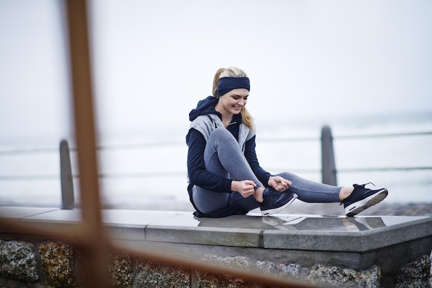 Photo time for these feet to hit the street shot of a young woman tying her shoelaces before a run