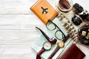 Time to travel concept hipster flat lay map passport money compass and glasses photo camera pipe on white wooden background top view planning vacation space for text wanderlust and explorexa