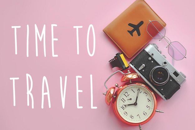 Photo time to travel text on passport with plane sunglassesphoto camera and clock on pink background modern travel and wanderlust image summer flat lay summer vacation