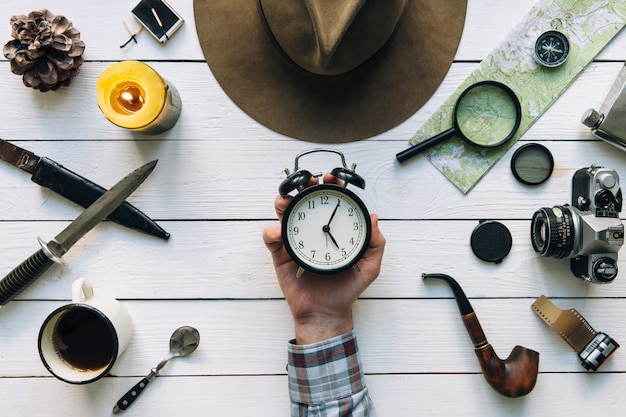 Time for travel with explorer hand holding vintage alarm clock