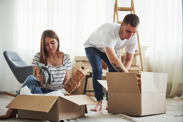 Time to unpack those boxes. Cheerful young couple in their new apartment. Conception of moving.