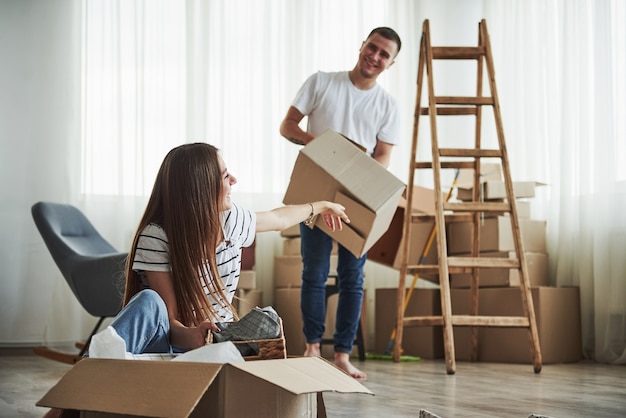 Time to unpack those boxes. Cheerful young couple in their new apartment. Conception of moving.