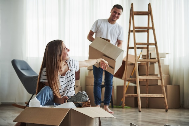 Time to unpack those boxes. Cheerful young couple in their new apartment. Conception of moving.