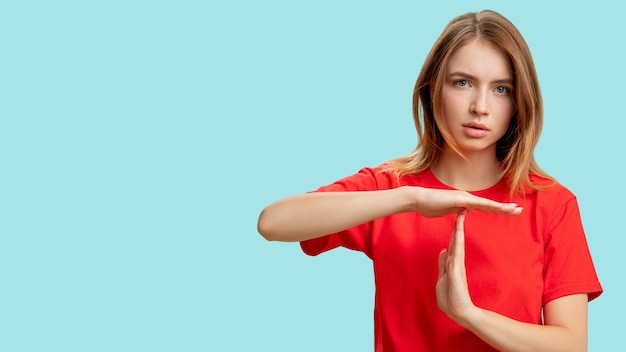 Time up Break gesture Portrait of confident protesting woman in red tshirt showing T sign with hands isolated on blue copy space background Restriction rejection Pause signal