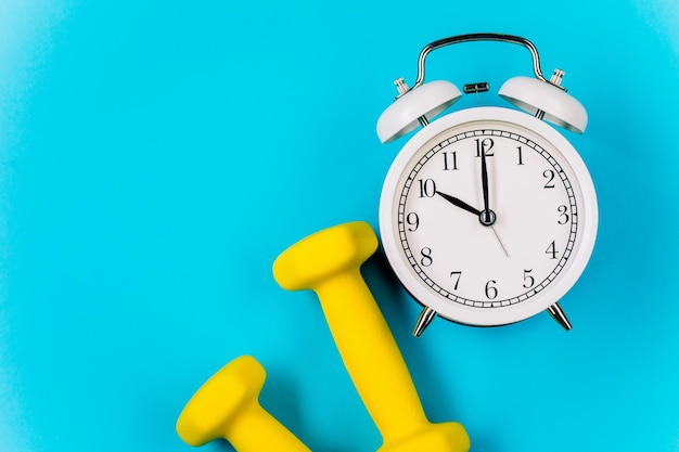 Time for workout clock and dumbbell with colorful blue background